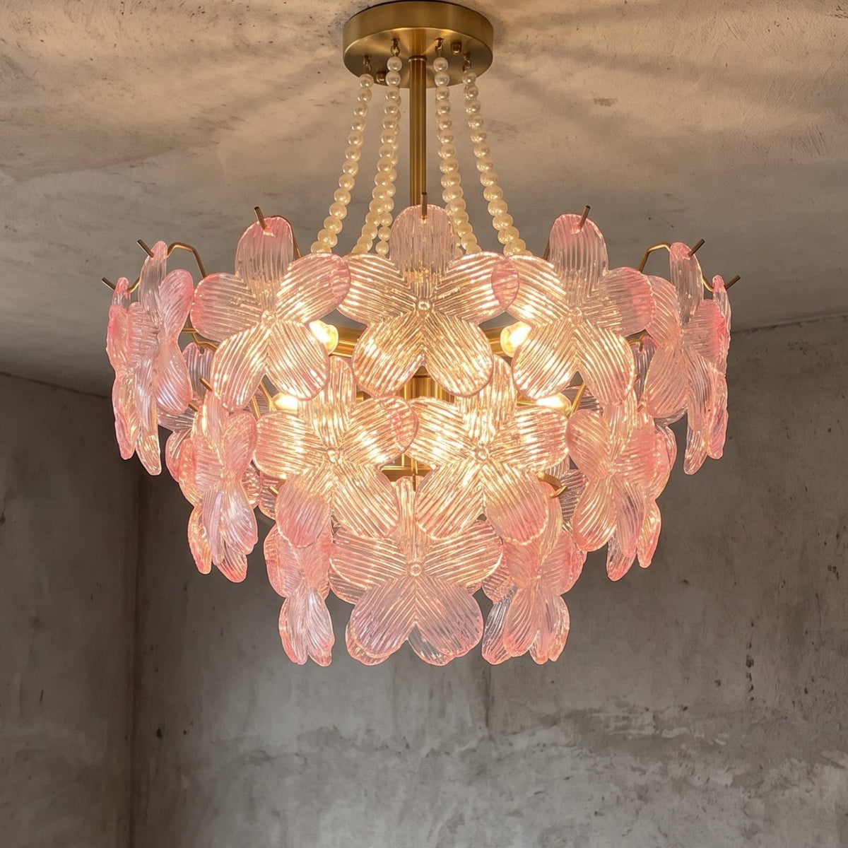 Lustre floral style Murano rose et transparent, vue d'ensemble, illuminant un salon moderne avec élégance et une lumière douce.
