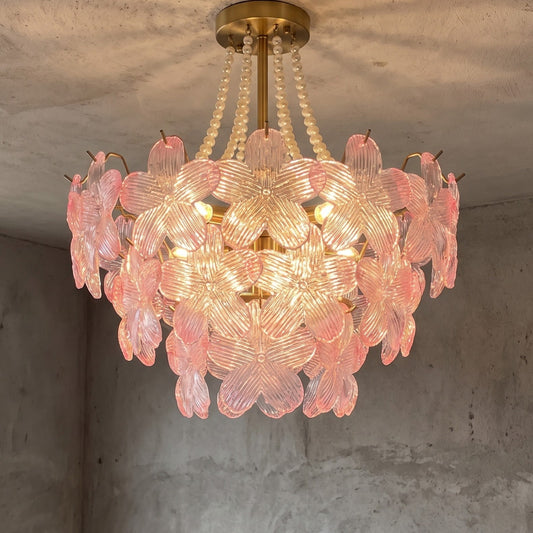 Lustre floral style Murano rose et transparent, vue d'ensemble, illuminant un salon moderne avec élégance et une lumière douce.