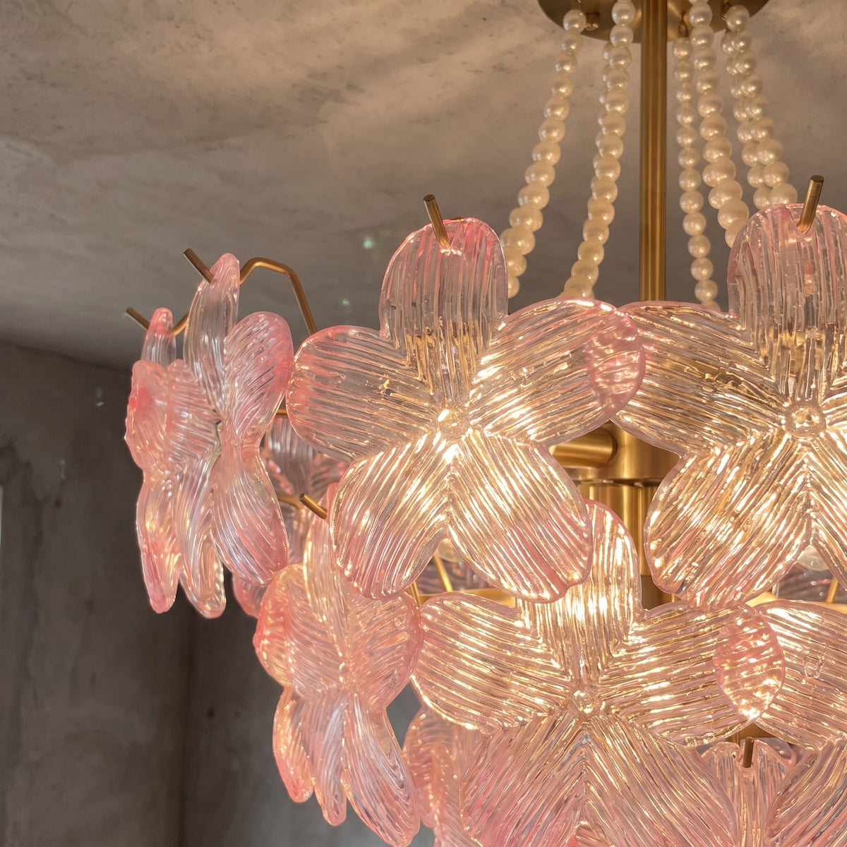 Le lustre style Murano rose éteint, montrant la beauté de ses formes et de ses matériaux dans une salle à manger lumineuse.