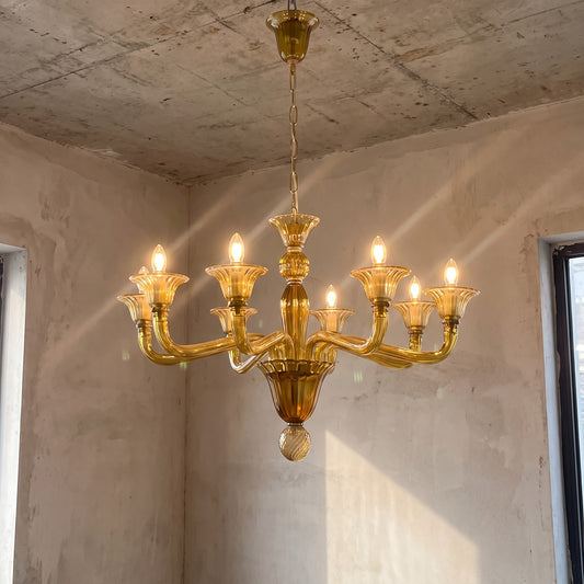 Vue d'ensemble du lustre style Murano vert ambré, illuminant un salon moderne avec élégance et chaleur. Ce luminaire est une pièce maîtresse.
