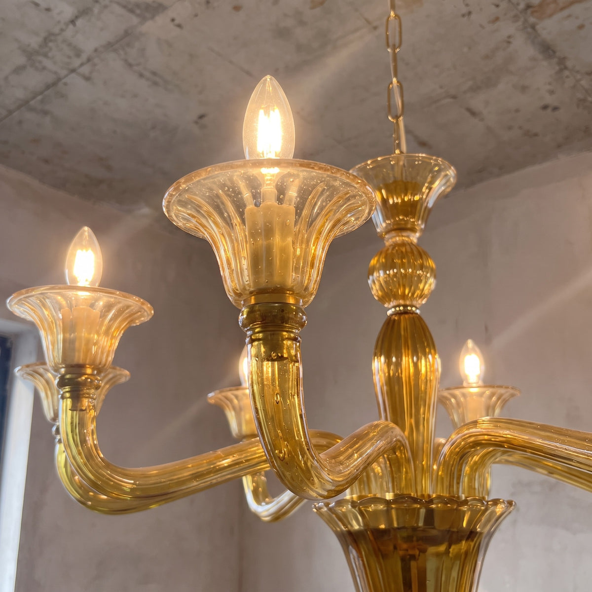 Lustre suspendu au-dessus d'une table de salle à manger, créant une ambiance sophistiquée avec ses 8 sources lumineuses E14 et son design.