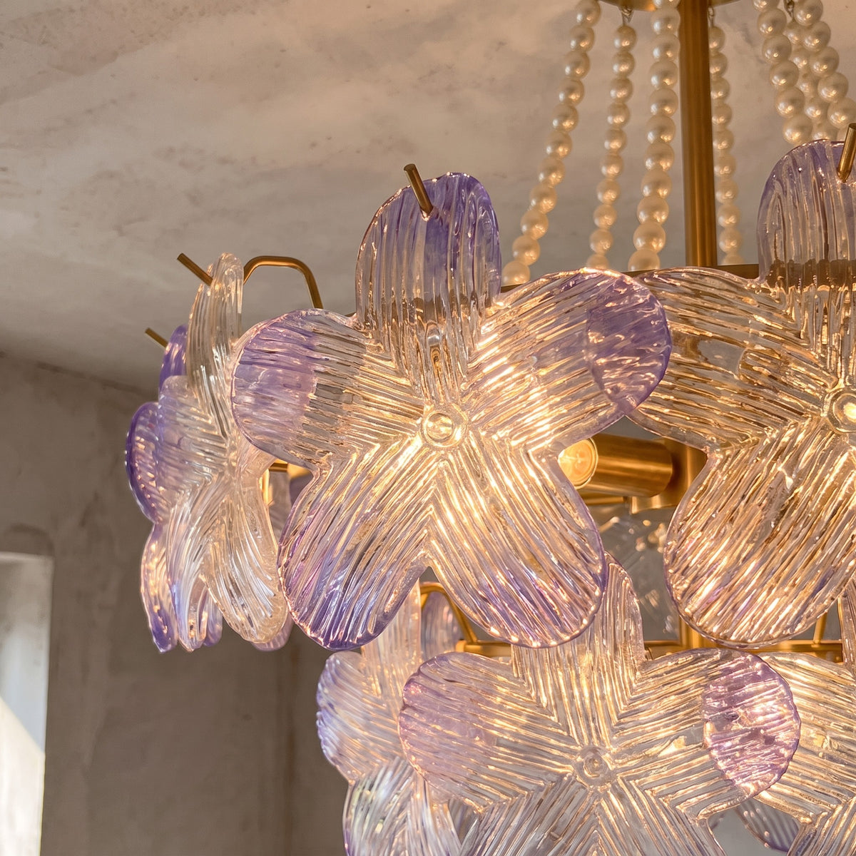 Détail rapproché des pétales de verre irisé aux reflets lavande du lustre, capturant la lumière diffuse et les textures uniques.