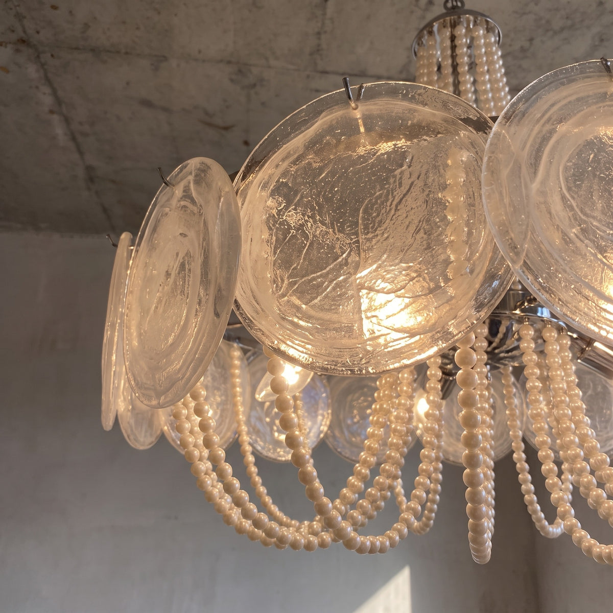 Lustre suspendu au plafond, illuminant une salle à manger moderne avec son élégance intemporelle et sa finition chromée.
