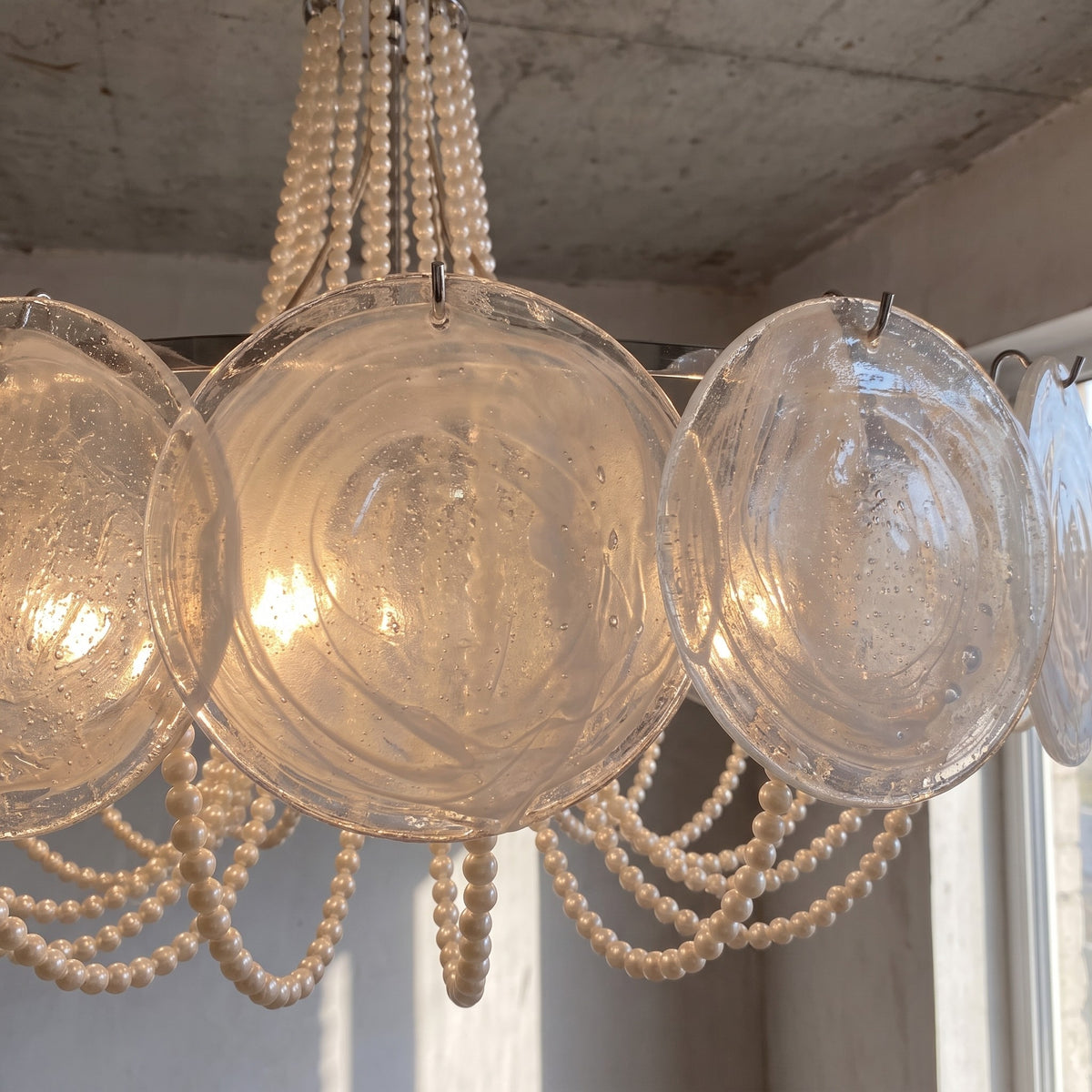 Plan rapproché des perles de verre et des éléments en verre irisé du lustre, montrant la qualité des matériaux et des reflets.