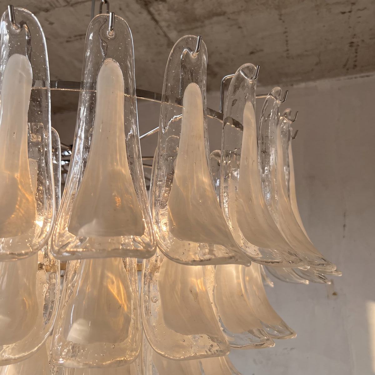 Détail des éléments en verre opalin texturé du lustre, reflétant la lumière chaude et mettant en valeur le savoir-faire inspiré de Murano.