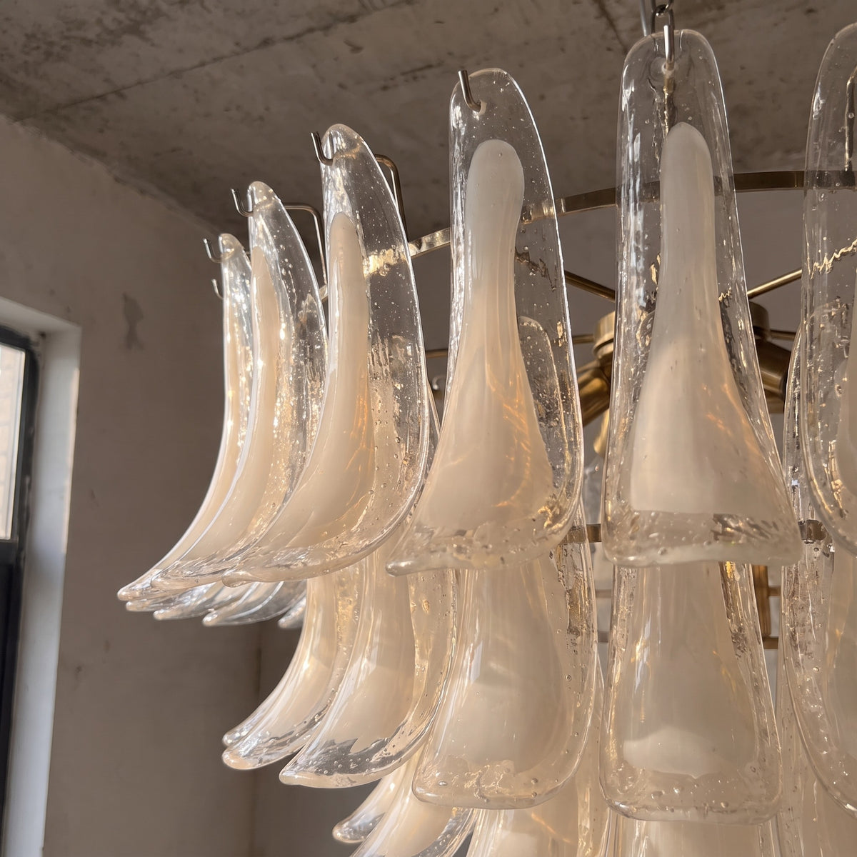 Lustre vénitien de 80 cm de diamètre avec ses pétales de verre soufflé blanc opalin, créant un design floral majestueux pour un salon.