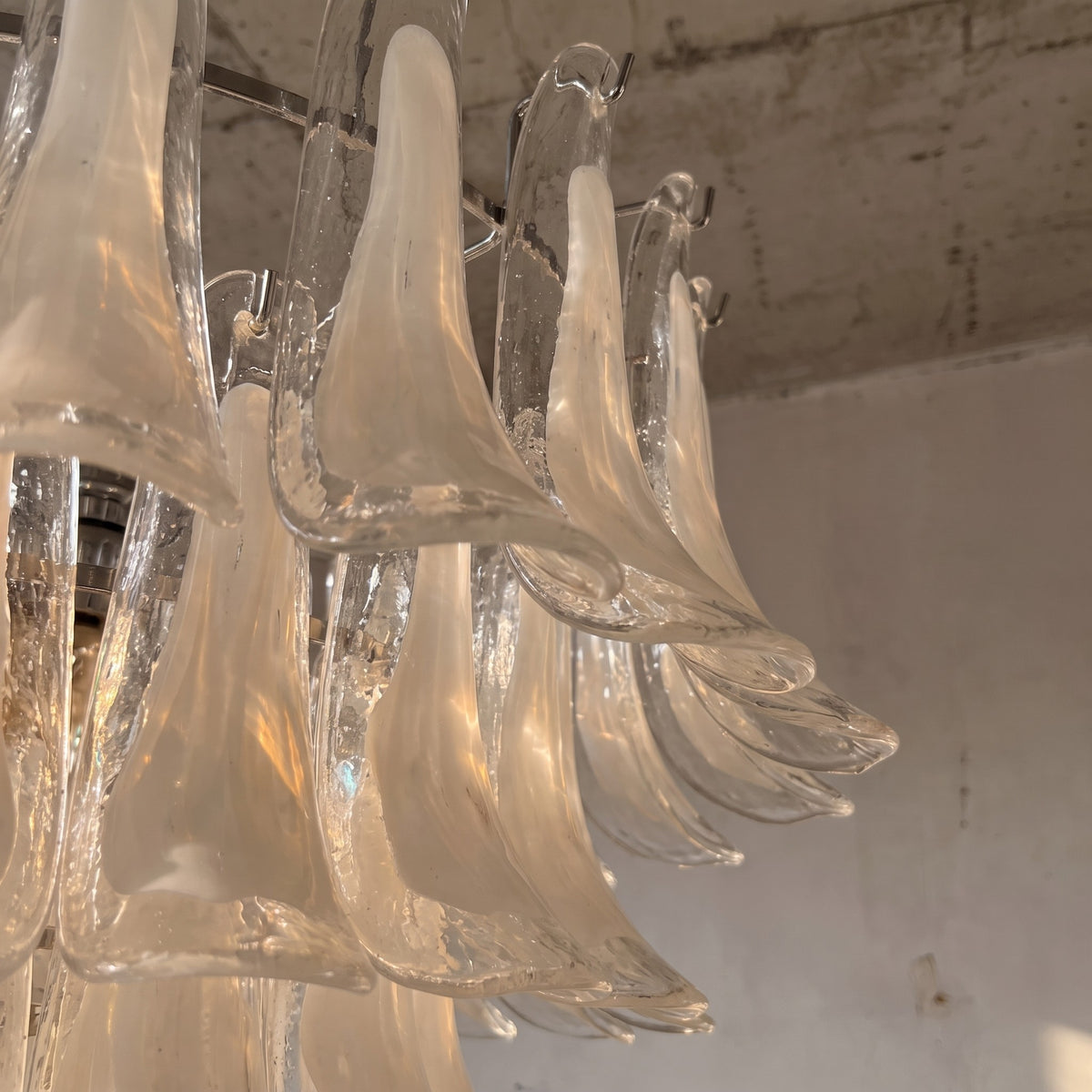 Lustre de salon de 68 cm de hauteur, présentant ses multiples niveaux de verre blanc opalin, une pièce maîtresse lumineuse et raffinée.