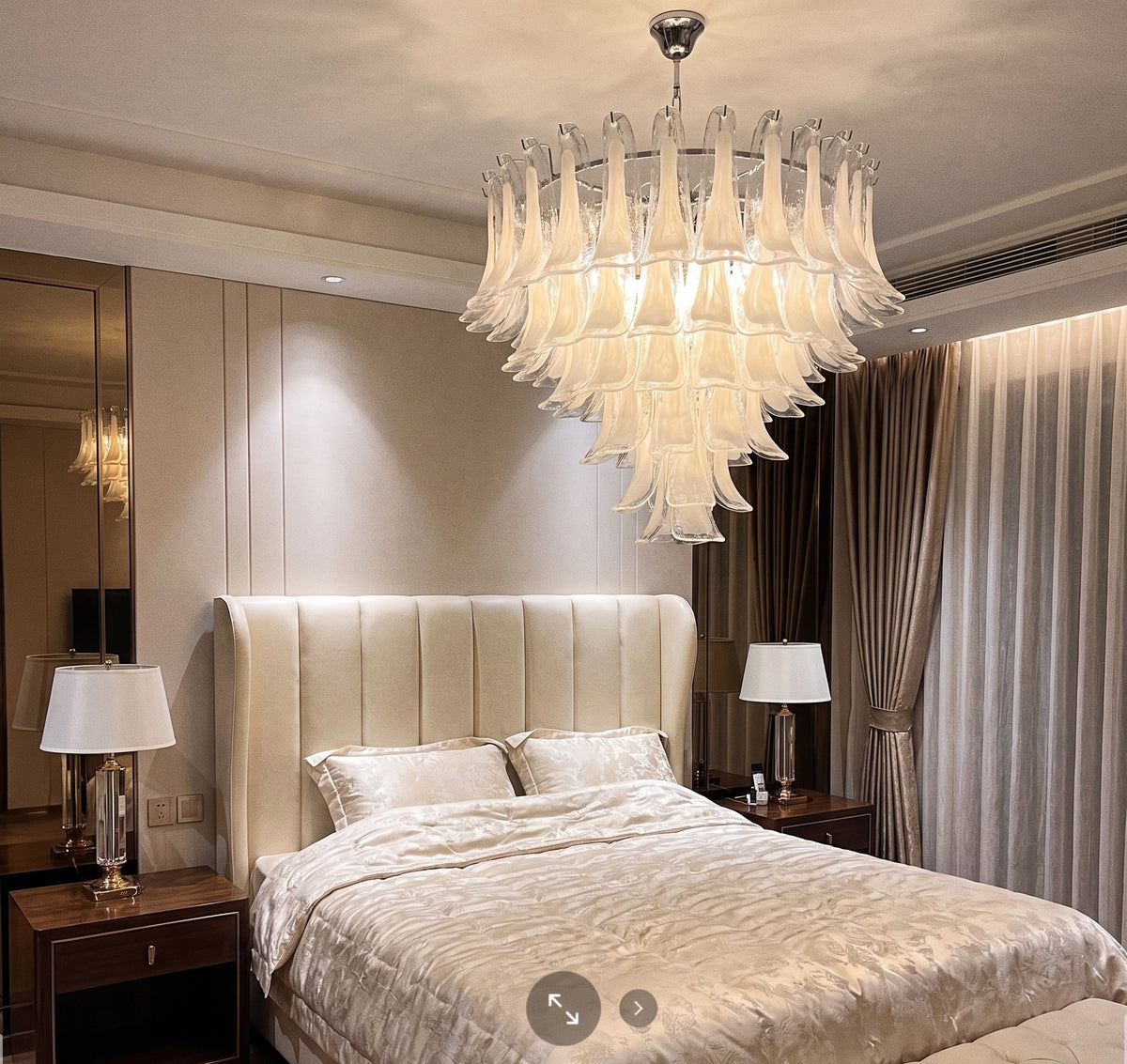 Le lustre éclairé, révélant la douce diffusion de lumière à travers le verre blanc opalin, parfait pour une ambiance chaleureuse dans une villa.