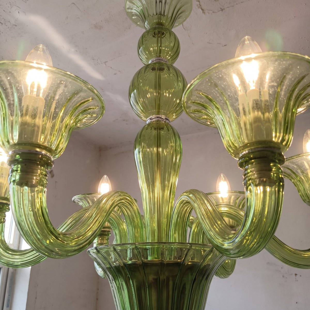 Détail du verre soufflé vert émeraude, capturant la lumière et montrant la texture délicate de chaque bras du luminaire Art Déco.