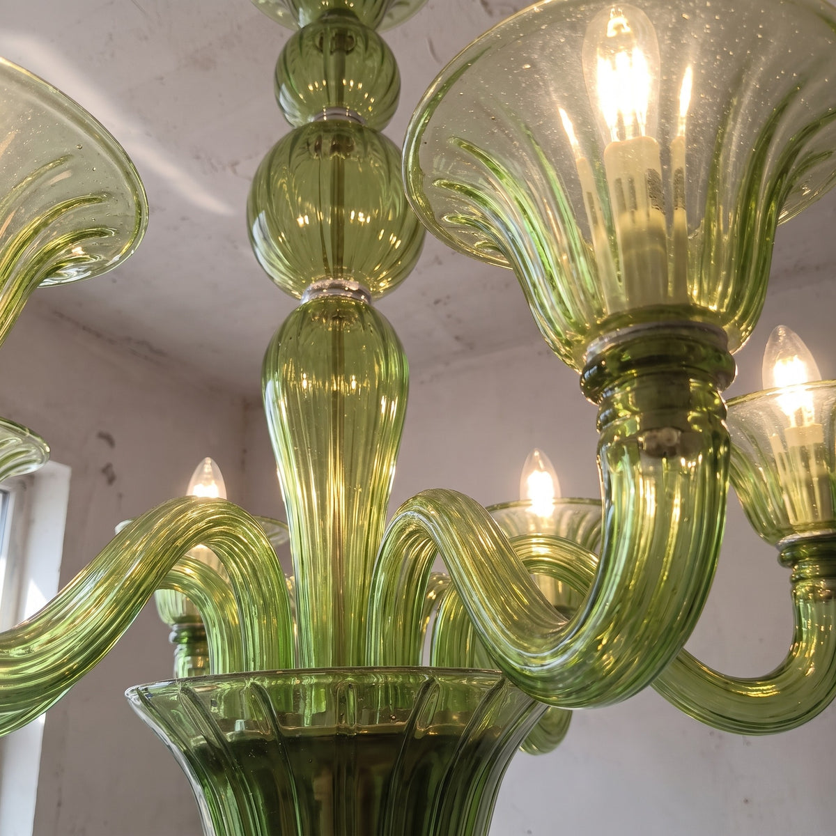 Gros plan sur le corps central du lustre en verre soufflé, révélant la complexité de sa forme et la richesse de sa couleur verte.