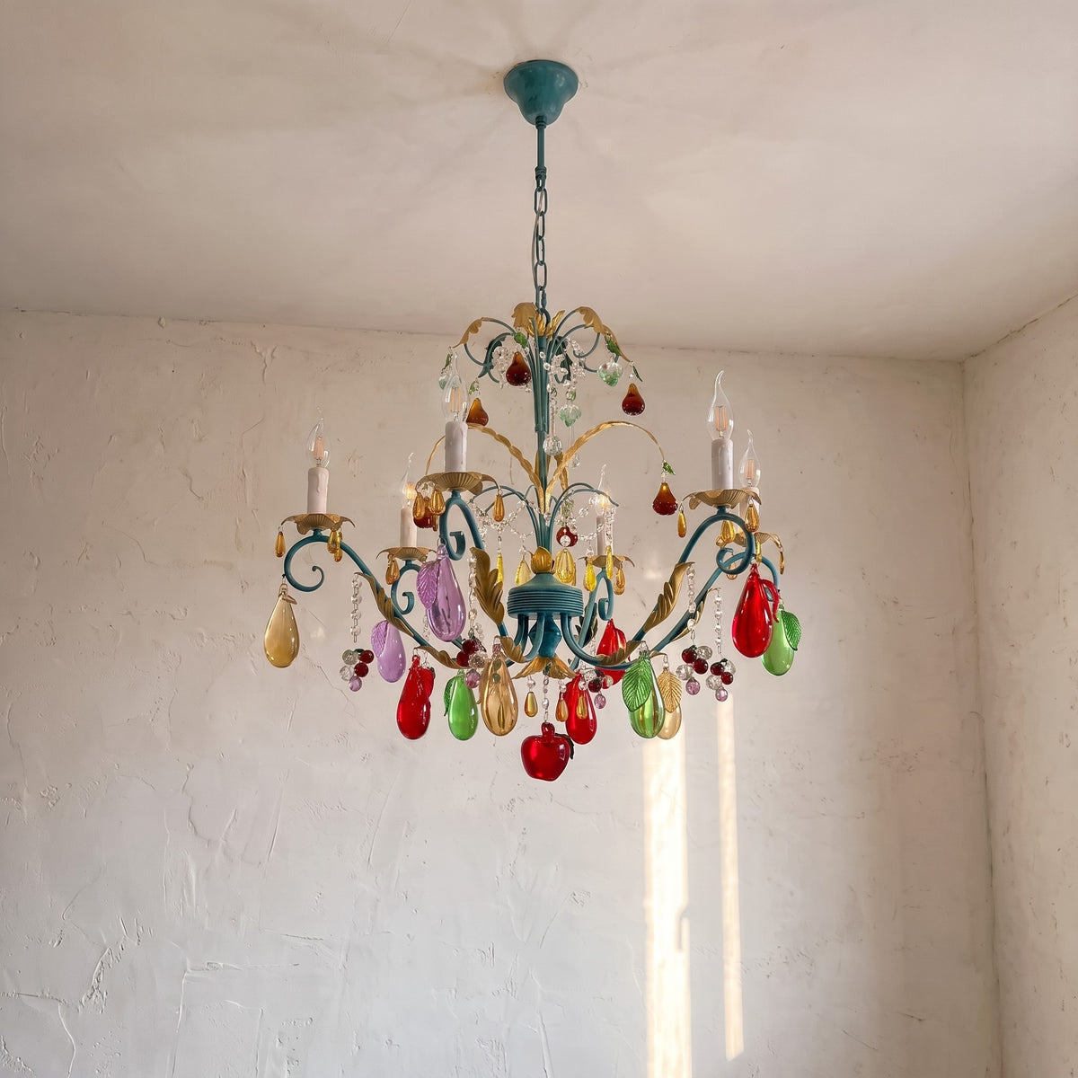 Angle montrant la chaîne de suspension et les motifs floraux dorés sur la structure métallique bleu-vert du lustre esprit vénitien.