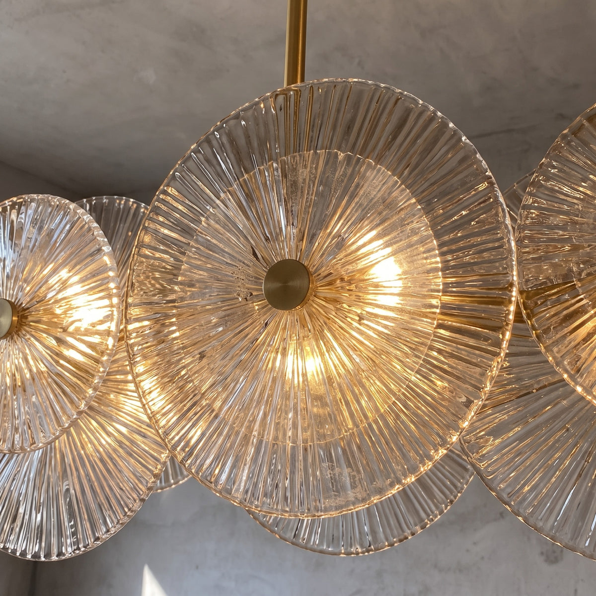 Lustre suspension doré avec ses ampoules LED allumées, créant une atmosphère chaleureuse dans un intérieur contemporain.