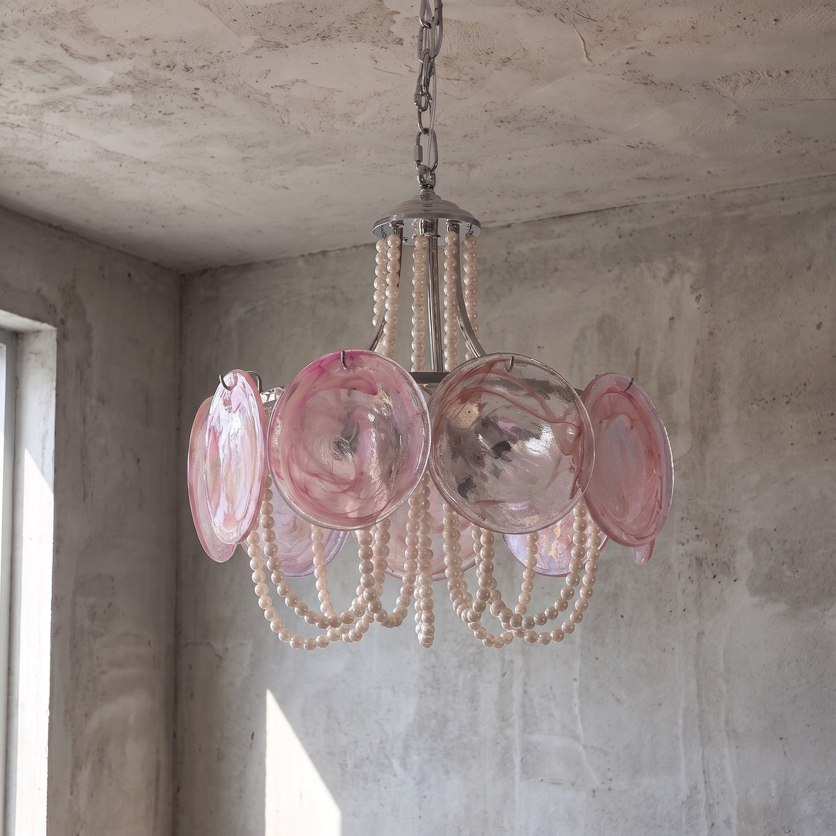 Détail rapproché du verre rose travaillé dans le style Murano, montrant les motifs uniques et la lumière diffuse du luminaire.