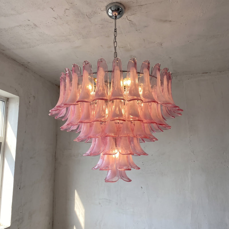 Lustre suspension rose style Murano en verre, vue d'ensemble, illuminant un salon moderne avec une lumière douce et chaleureuse.