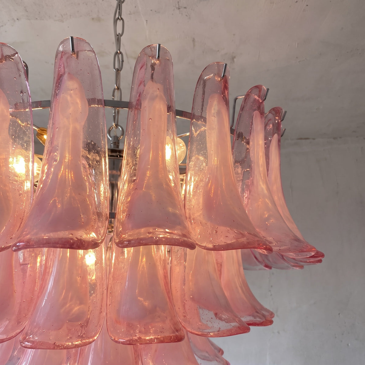 Installation du lustre suspension style Murano rose, mettant en évidence la chaîne ajustable et la finition chrome poli du support.