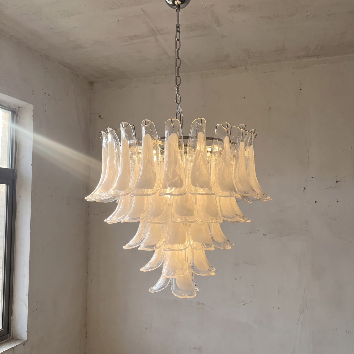 Lustre suspension grand modèle style Murano en verre blanc opalin, illuminant un salon moderne avec élégance et design vintage.