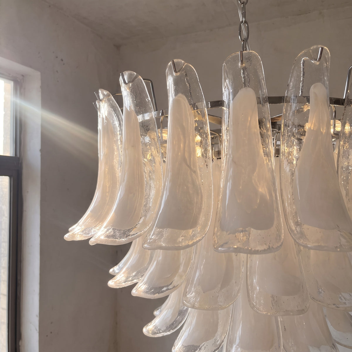 Lustre suspension allumé, révélant la douce diffusion de lumière à travers ses éléments en verre, idéal pour une chambre.