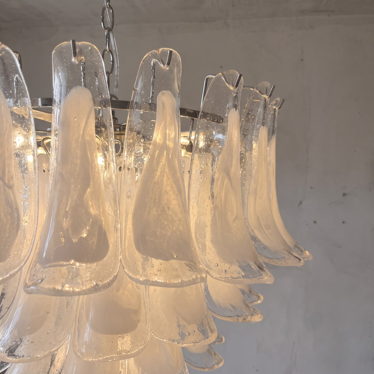 Profil du lustre style Murano, montrant ses multiples couches de verre blanc et sa structure métallique chromée polie.