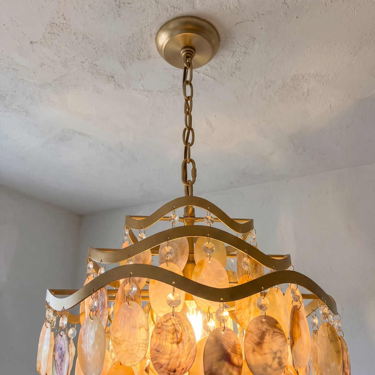 Le lustre suspension doré avec ses perles de verre scintillantes, créant une ambiance lumineuse chaleureuse et raffinée.
