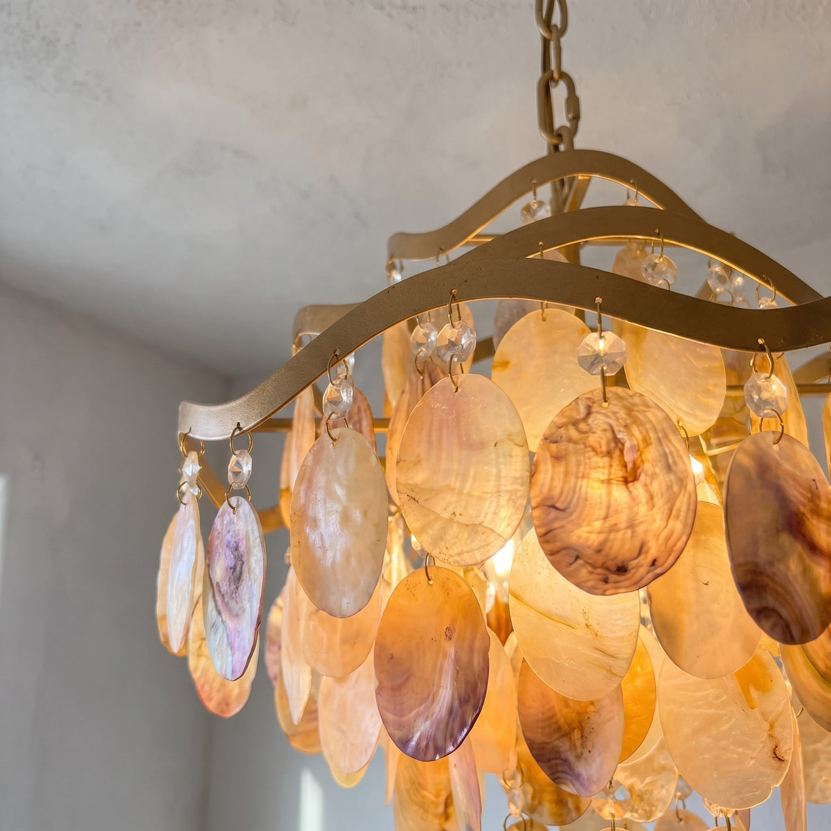Vue d'ensemble du lustre suspension vénitien en alliage doré, mettant en valeur ses multiples rangées de coquilles irisées.