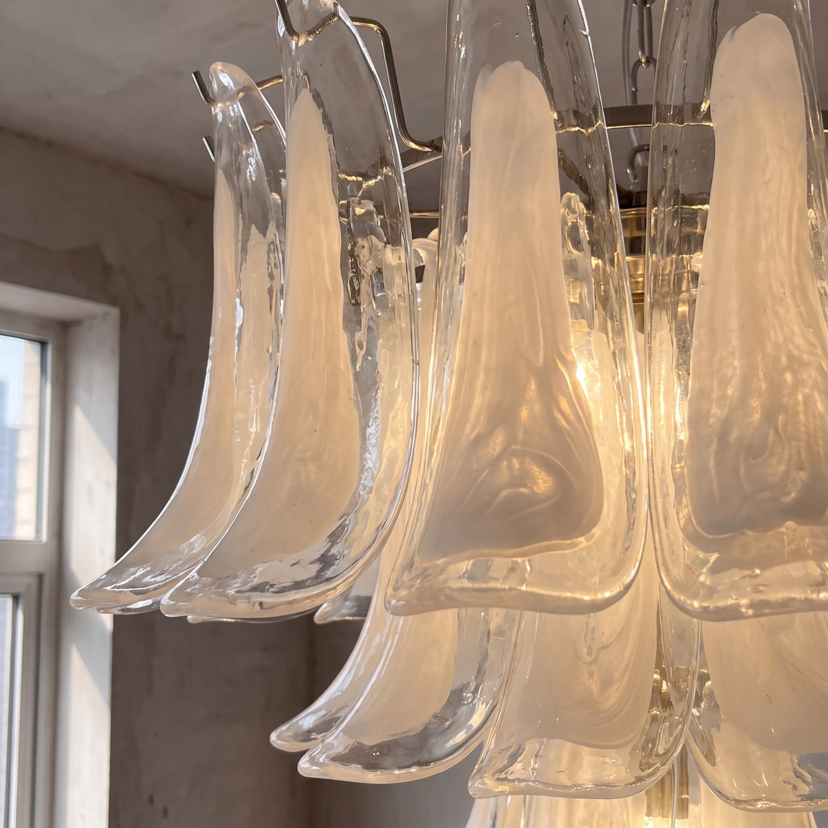 Lustre allumé, mettant en valeur l'éclat du verre opalin blanc et la finition chrome poli de la fixation supérieure.
