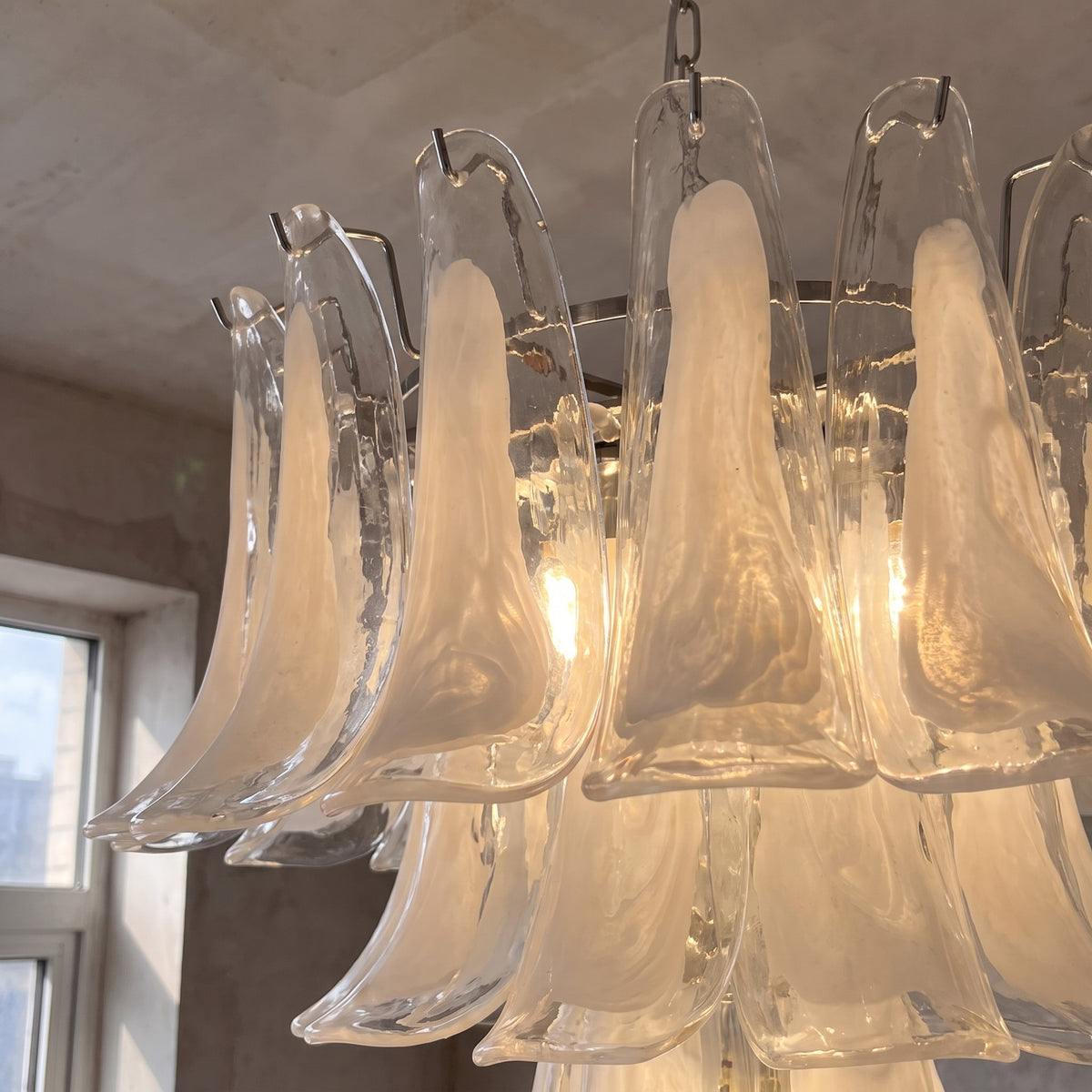 Détail des pétales en verre opalin blanc du lustre style Murano, révélant la texture et la diffusion douce de la lumière.