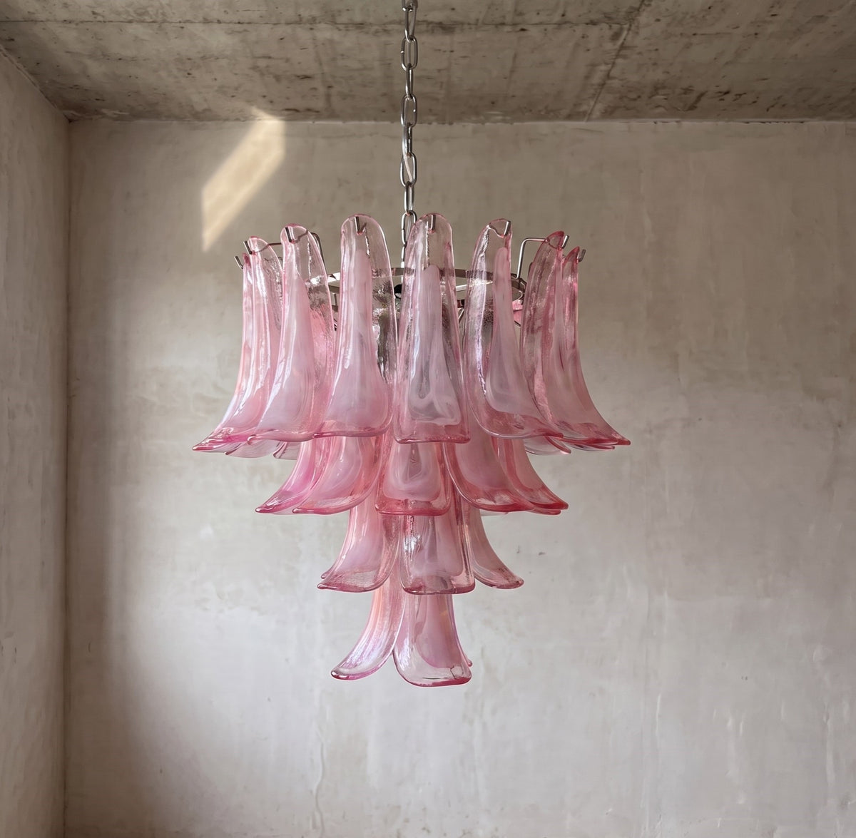 Vue latérale d'un lustre suspension rose, mettant en évidence la superposition des pétales de verre qui composent sa silhouette unique et artistique.