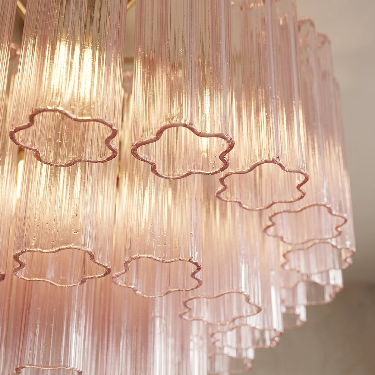Lustre semi-encastré en verre rose vu de profil, soulignant sa forme ronde et ses multiples couches de verre décoratif.