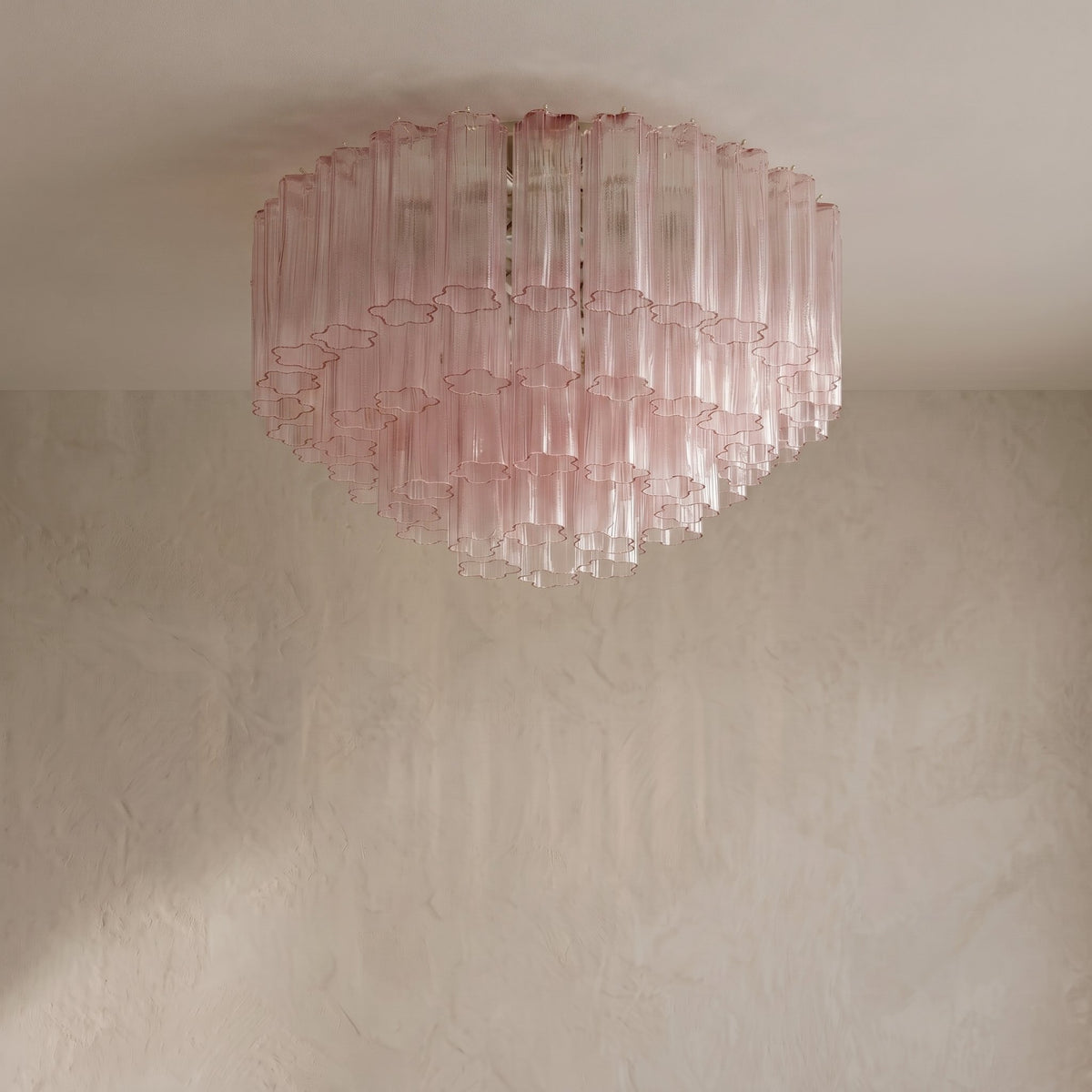 Ambiance lumineuse créée par le lustre en verre rose allumé, projetant une douce clarté dans la pièce. Hauteur 51 cm.