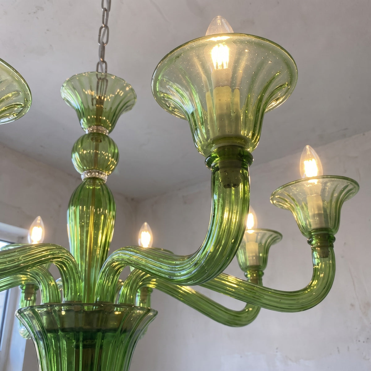 Lustre suspension vert Art Déco illuminé, diffusant une lumière douce et chaleureuse idéale pour un salon spacieux et moderne.