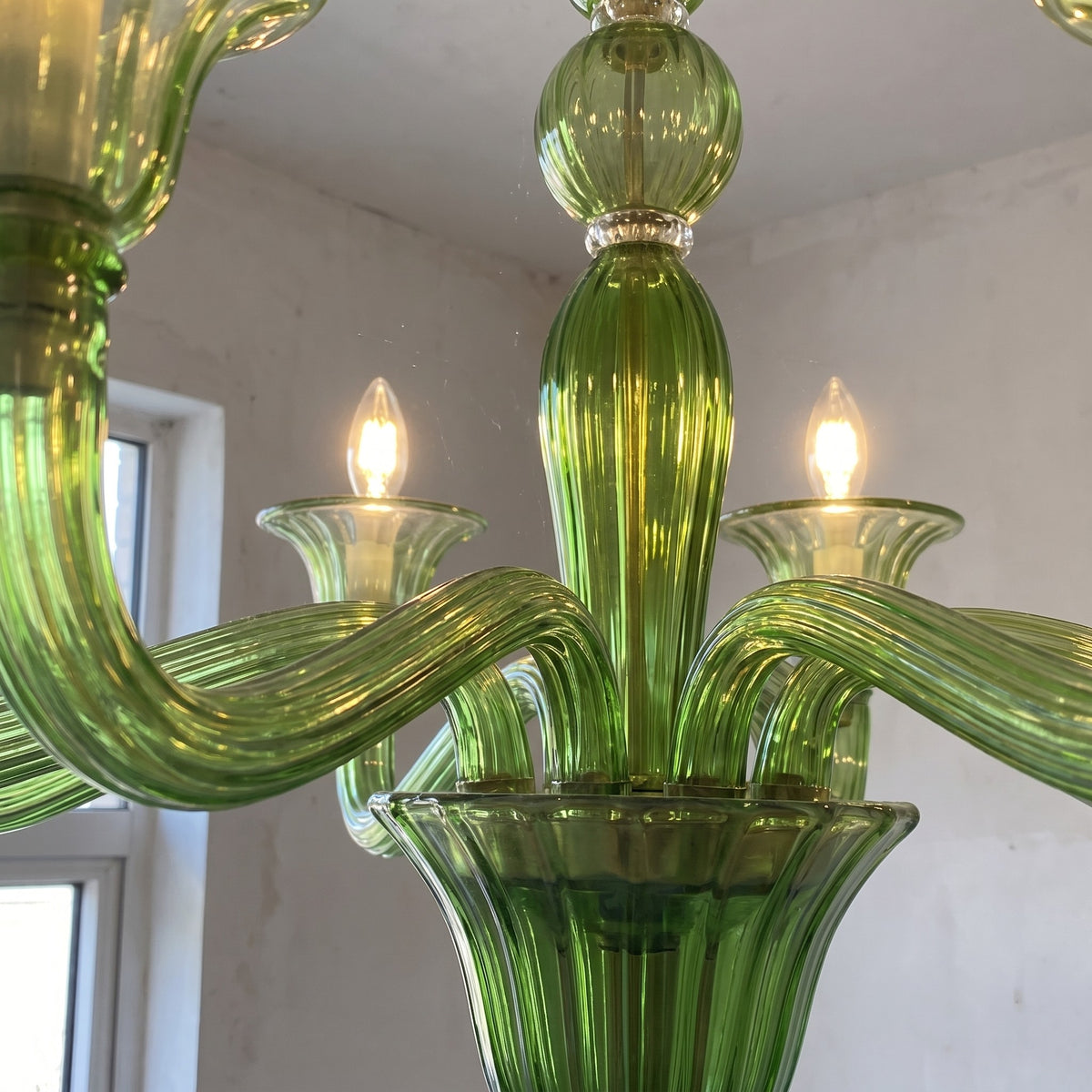 Perspective du lustre en verre vert dans une chambre, soulignant son design intemporel et son adaptation à divers espaces de vie.