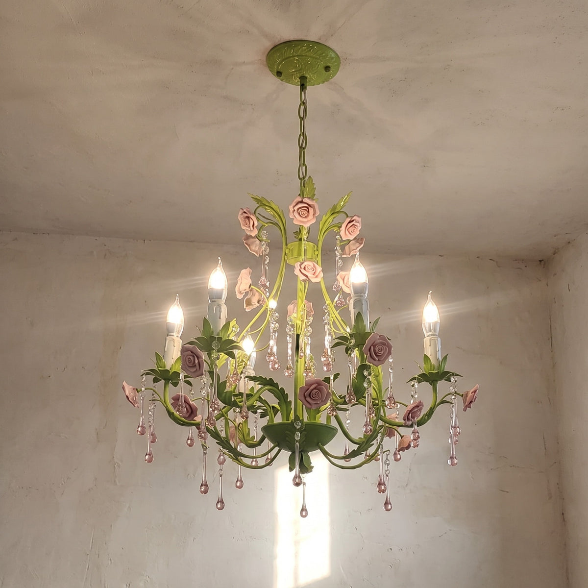 Lustre de style campagnard français suspendu, mettant en valeur sa structure métallique vert pastel et ses ornements floraux.