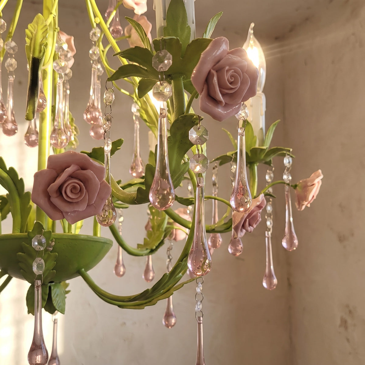 Image du lustre éteint, révélant la beauté de ses matériaux : métal vert, céramique rose et cristaux transparents, pour la chambre.