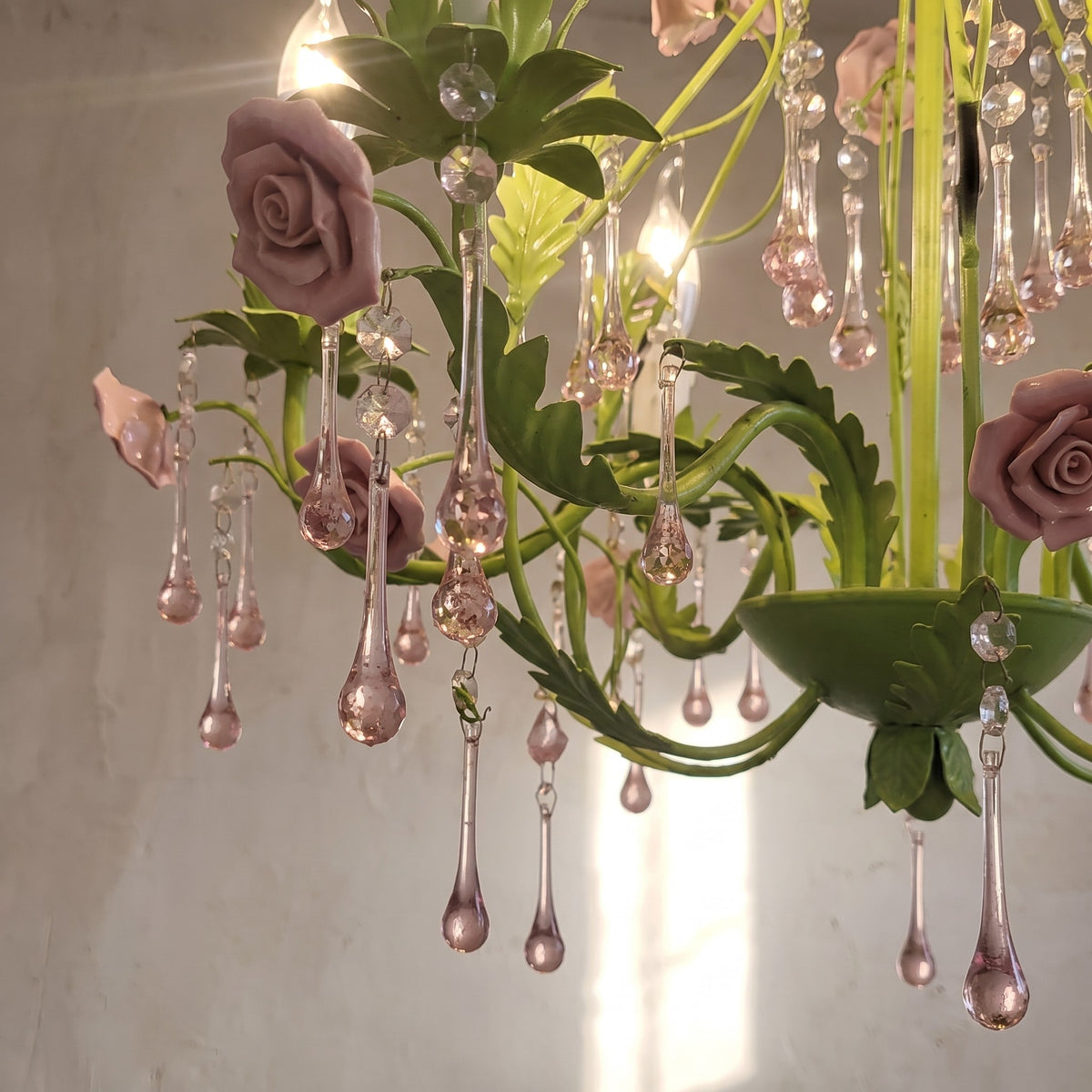 Lustre vert pastel floral avec ses cinq ampoules E14 allumées, montrant son design campagnard français élégant dans un intérieur chaleureux.