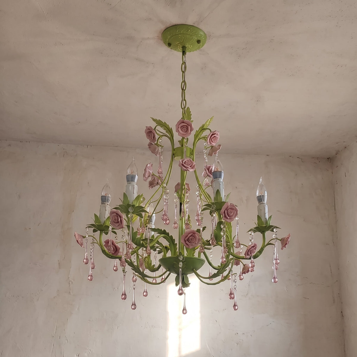 Détail rapproché des roses en céramique rose et des cristaux scintillants, soulignant la finesse artisanale de ce lustre floral.