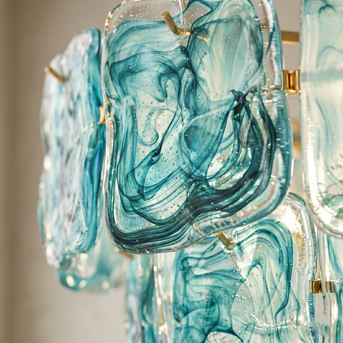 Vue rapprochée des éléments en verre teinté bleu-vert du lustre, révélant les motifs marbrés uniques inspirés de l'art vénitien.