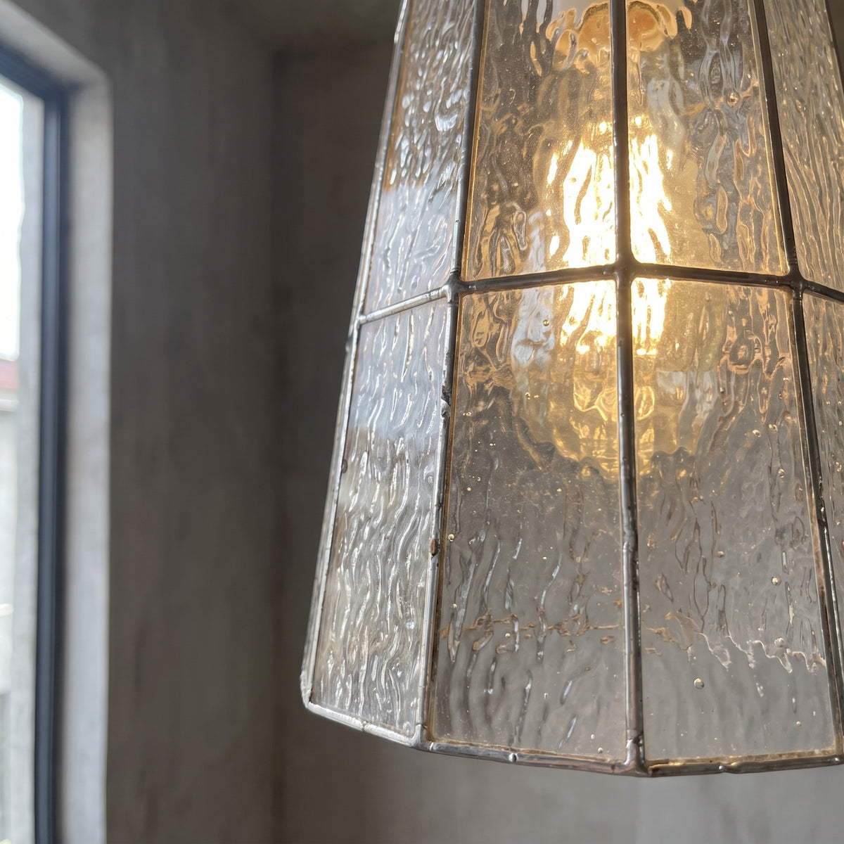 Ambiance chaleureuse créée par la suspension Art Déco allumée, le verre clair texturé diffuse une lumière douce et accueillante.