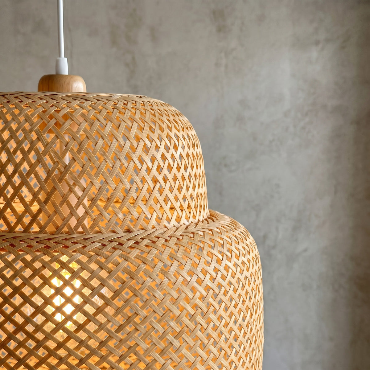 Luminaire suspendu en bambou de 30 cm de diamètre, avec câble réglable, apportant une touche organique et apaisante à la pièce.