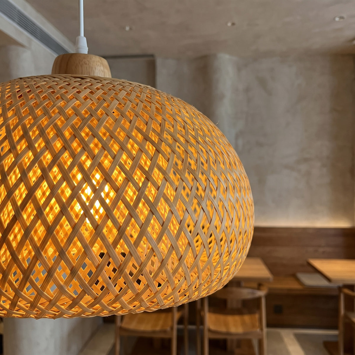 La suspension en bambou tressé allumée, projetant des motifs lumineux délicats sur le mur, ajoutant du caractère à la pièce.