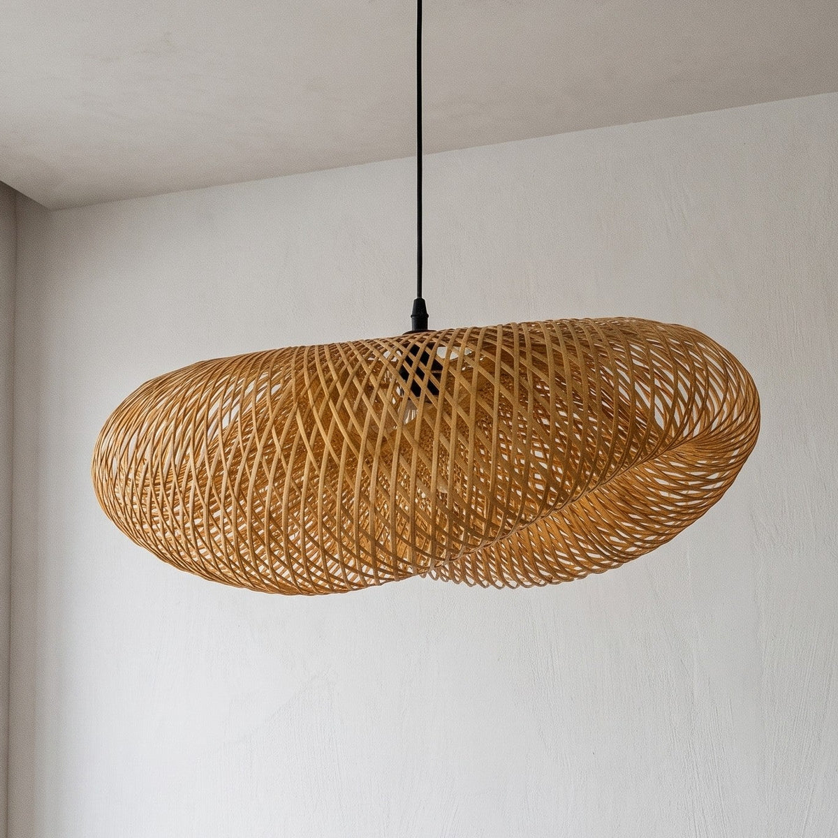 Suspension LED en bambou naturel tressé de 80 cm de diamètre, éclairant un salon moderne avec une lumière douce et chaude.