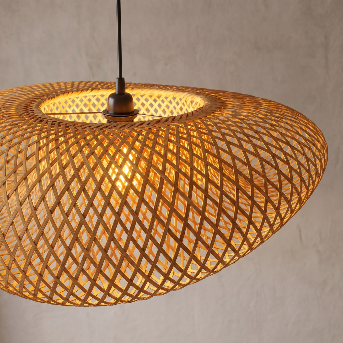 Détail de la fixation du câble noir et de la structure interne métallique de la suspension LED en bambou, mettant en valeur son design épuré.