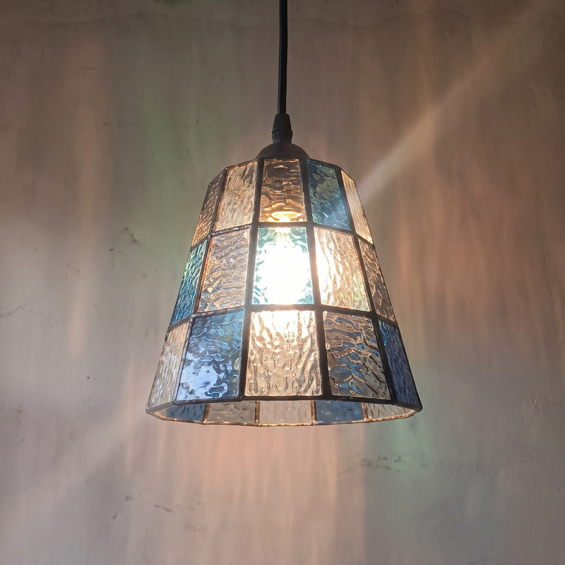 Suspension style Murano vintage en verre texturé bleu et ambré, éclairant un coin lecture avec une lumière douce et colorée.