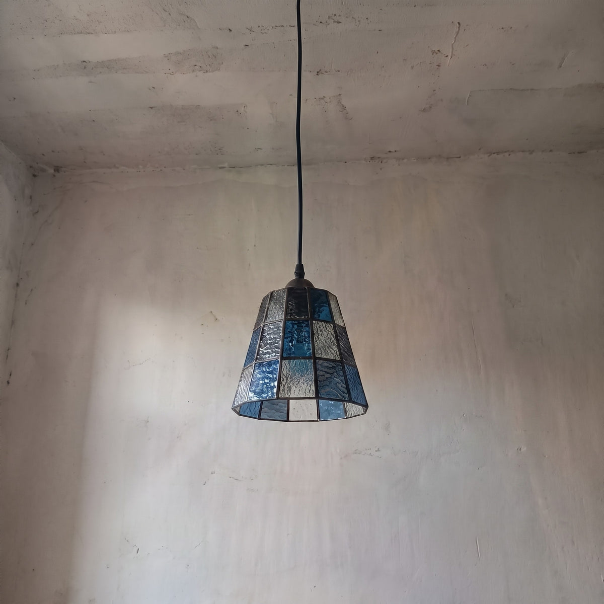 Suspension élégante en verre texturé bleu et ambré, suspendue au-dessus d'un îlot de cuisine pour une ambiance Art Déco unique.