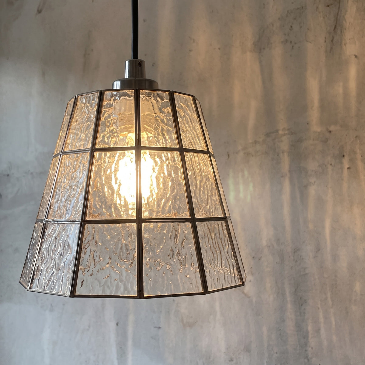 Gros plan sur l'assemblage des panneaux de verre texturé et le cadre en fer forgé, soulignant la qualité de fabrication.