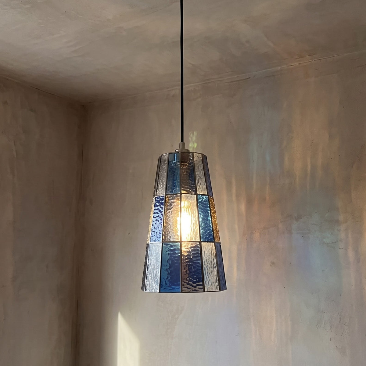 Suspension en verre teinté bleu ambré, vue d'ensemble, avec son abat-jour conique et son câble réglable.