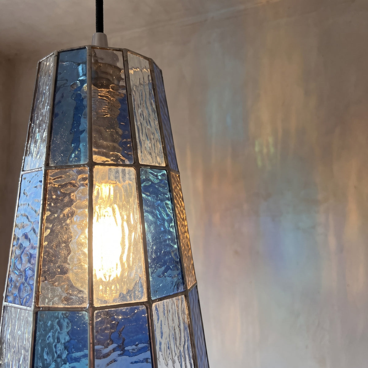 Suspension en verre teinté installée dans une cuisine moderne, ajoutant une touche de couleur et d'élégance.