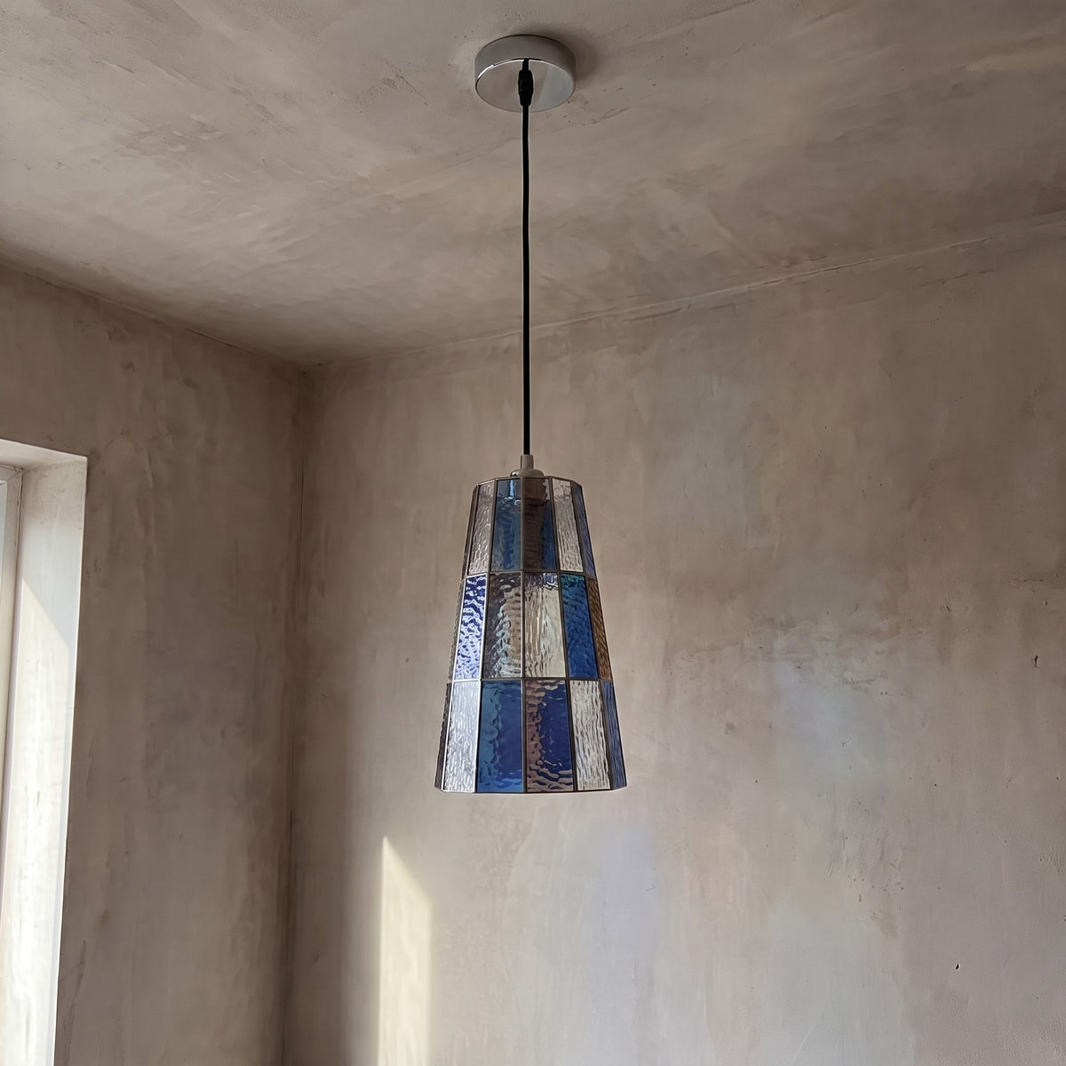 Détail rapproché de la mosaïque de verre teinté bleu et ambré, révélant la texture unique des pièces.