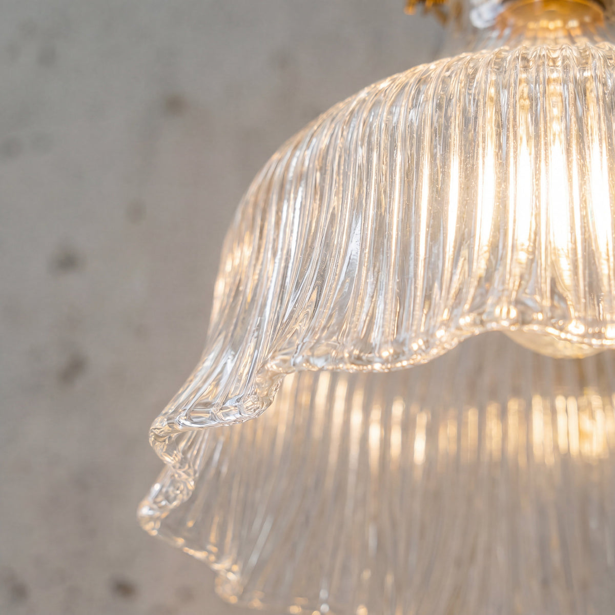 Vue détaillée de l'abat-jour en verre cannelé de l'applique murale, révélant sa texture délicate et sa diffusion lumineuse douce.