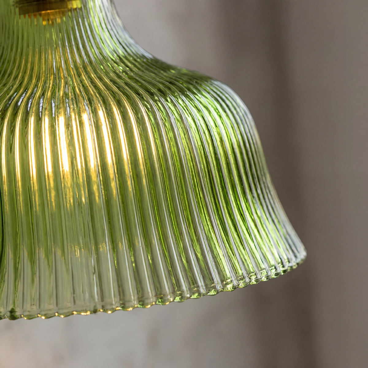 Gros plan sur le culot E27 de l'applique murale en laiton, visible sous l'abat-jour en verre cannelé vert, prête à accueillir une ampoule LED.