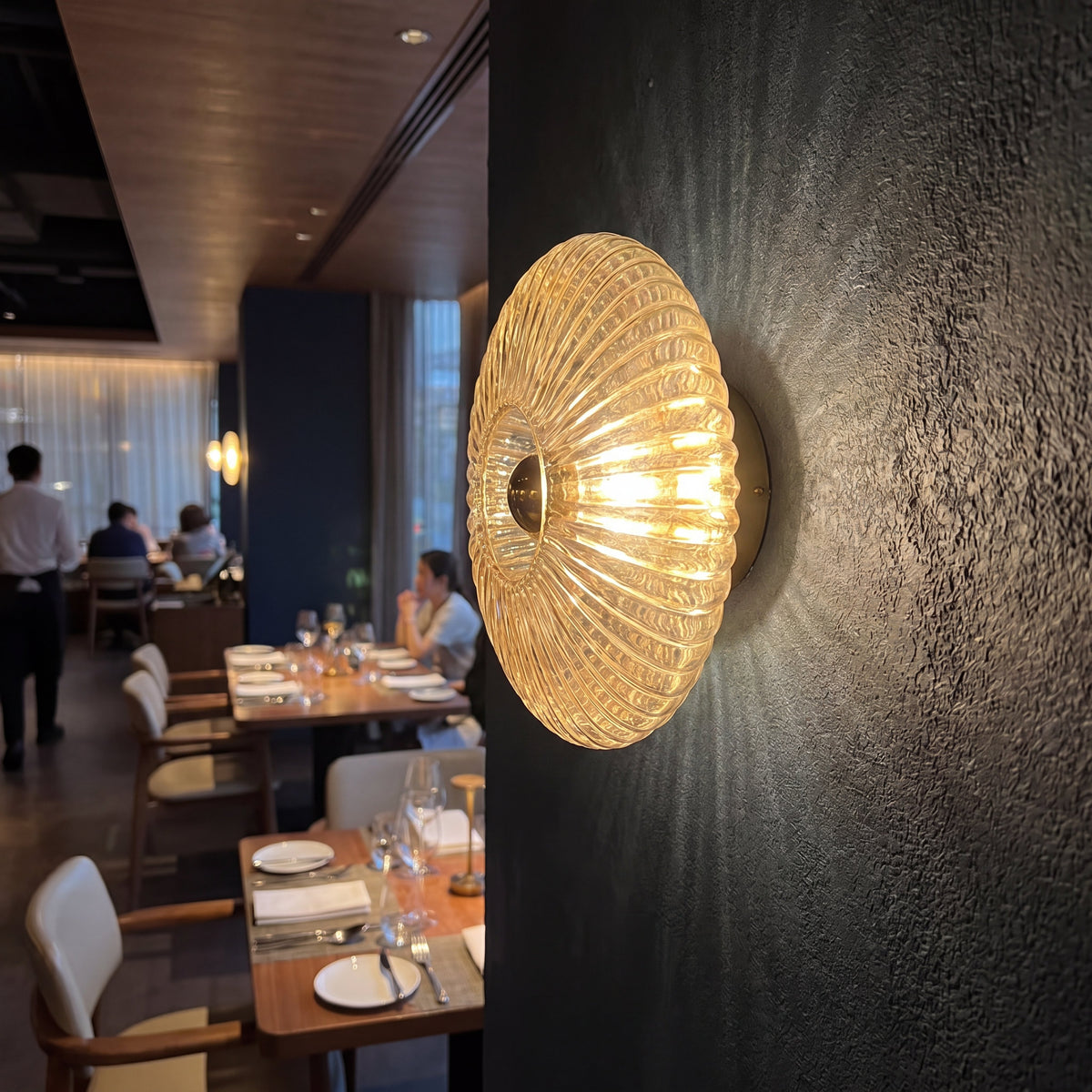 Applique murale en verre cognac illuminant un couloir, créant une ambiance chaleureuse et accueillante avec sa lumière douce.